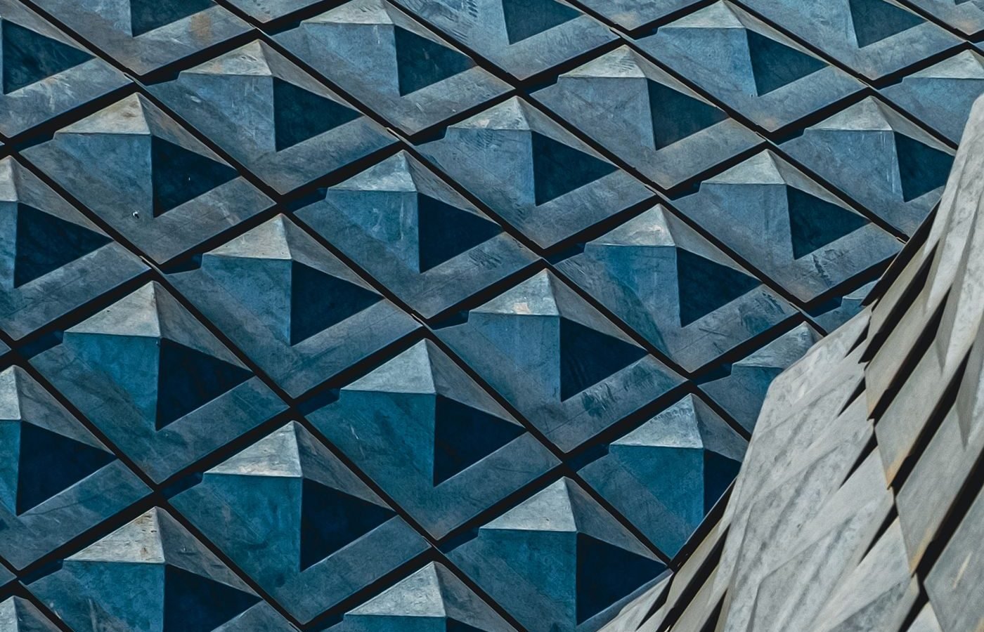 Blue-grey faceted building facade of repeating diamond panels